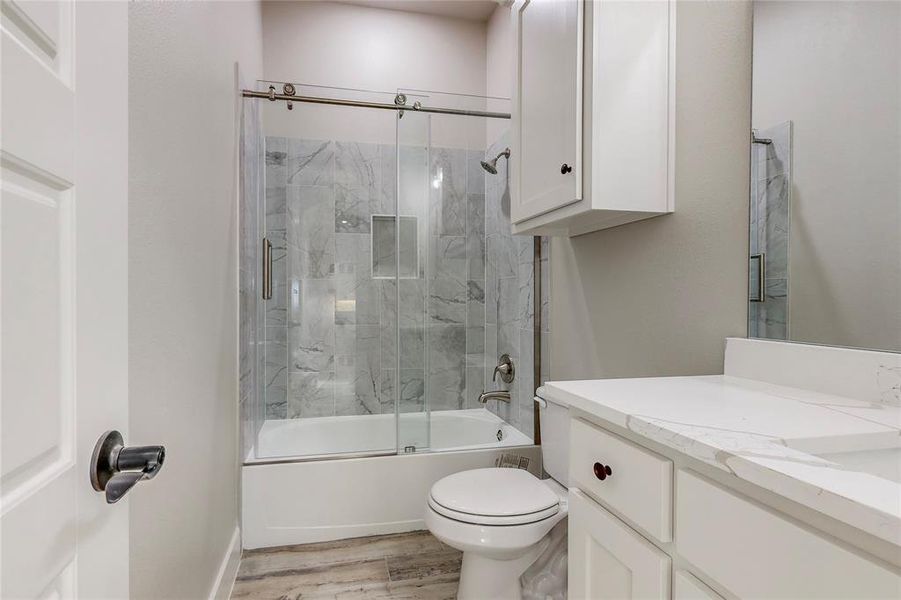 Full bathroom featuring toilet, combined bath / shower with glass door, hardwood / wood-style flooring, and vanity