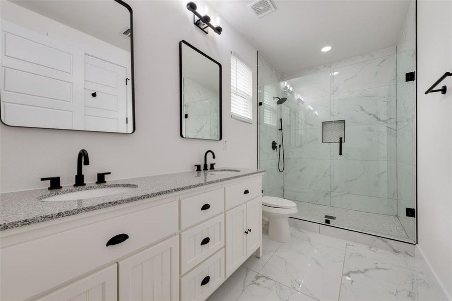 Bathroom with vanity, toilet, and a shower with shower door