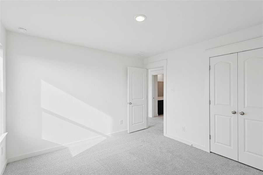 Unfurnished bedroom featuring light carpet and a closet