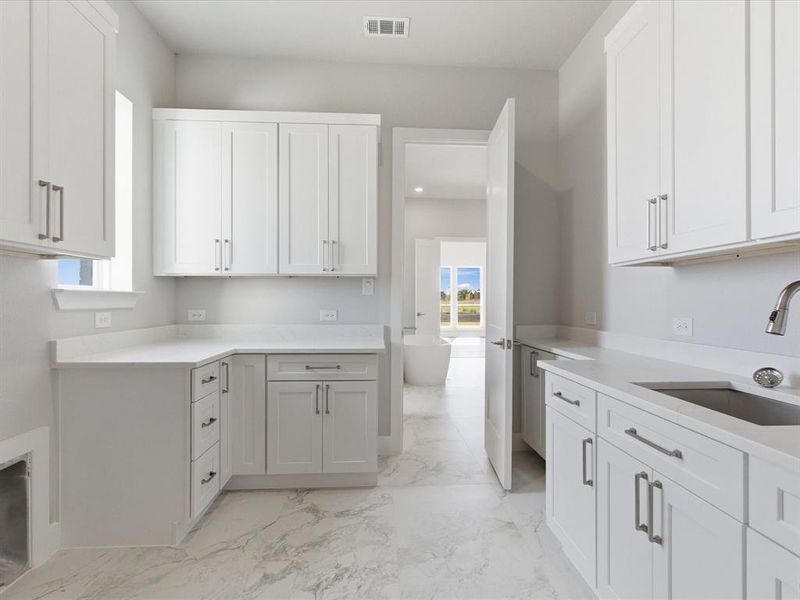 Kitchen with healthy amount of natural light, white cabinetry, and light marble finish flooring