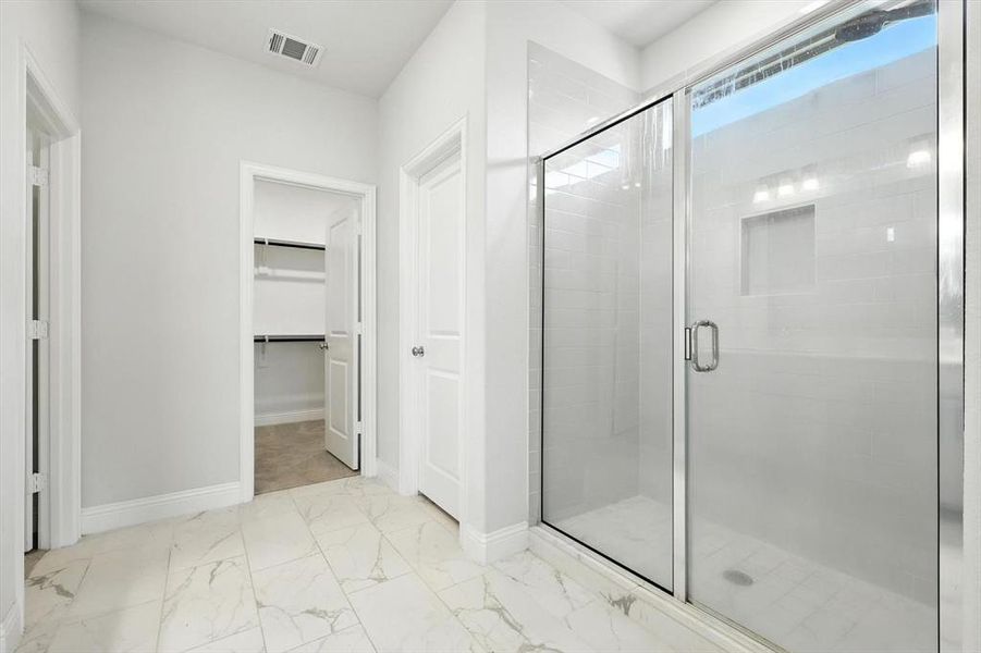 Large primary bath with walk in closet, built in cabinets, dual sinks, linen and natural light
