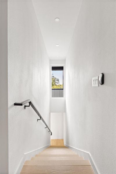 Stairway with a textured wall, wood finished floors, and recessed lighting