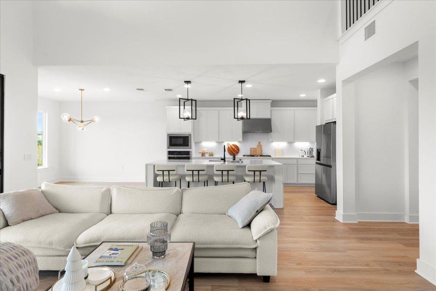 Living room with recessed lighting, light wood finished floors, and a chandelier Living room with recessed lighting, light wood finished floors, and a chandelier