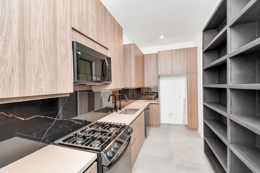 Additional full working kitchen behind the main kitchen with gas range, microwave, sink, and dishwasher.