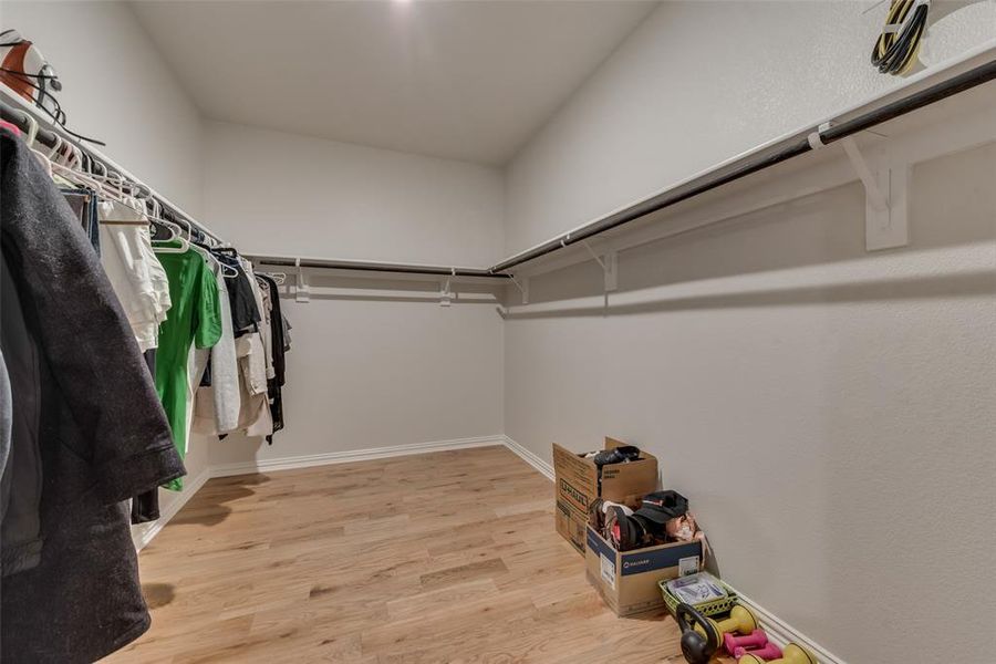 Spacious master bedroom closet with hardwood flooring