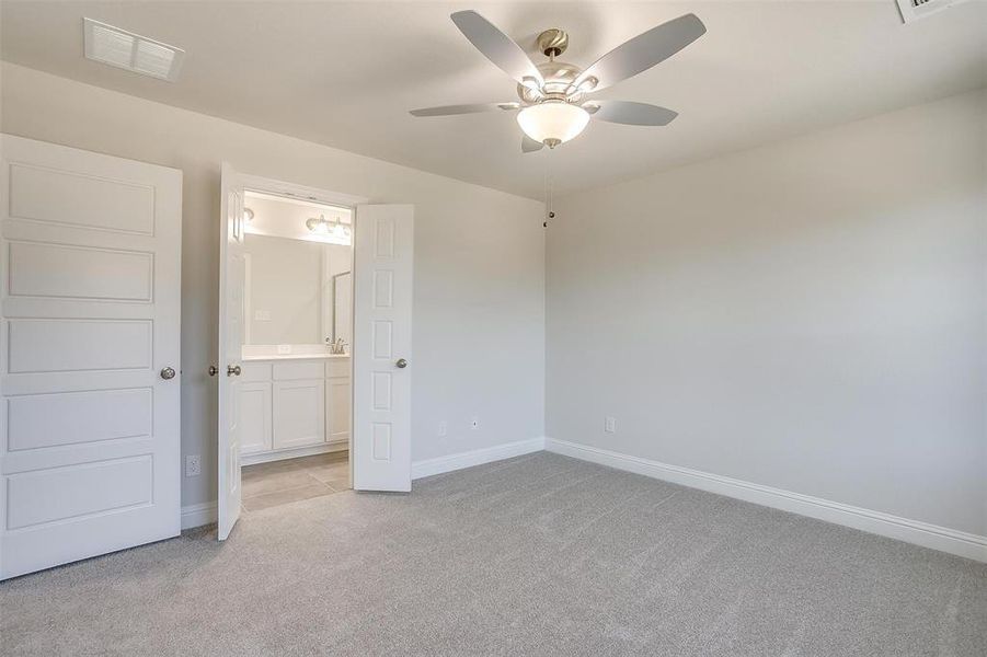 Unfurnished bedroom with light colored carpet, a ceiling fan, and ensuite bathroom Unfurnished bedroom with light colored carpet, a ceiling fan, and ensuite bathroom
