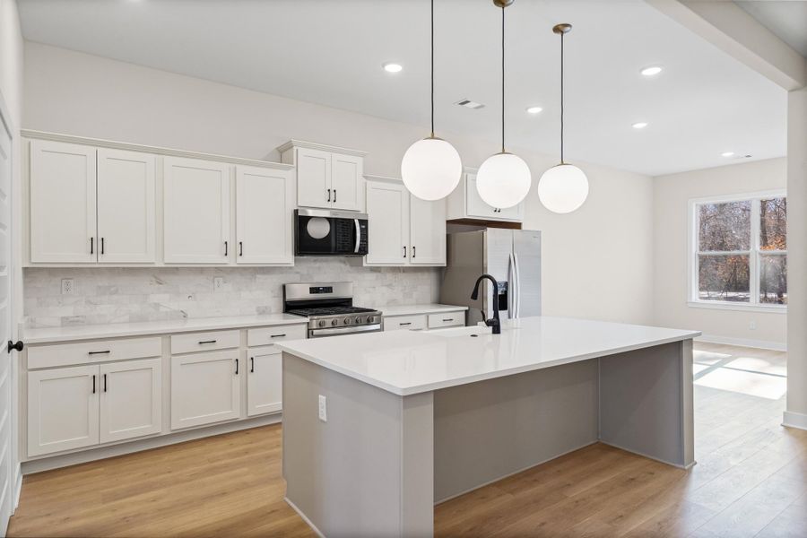 Kitchen with light wood-type flooring, stainless steel appliances, white cabinetry, and pendant lighting Kitchen with light wood-type flooring, stainless steel appliances, white cabinetry, and pendant lighting