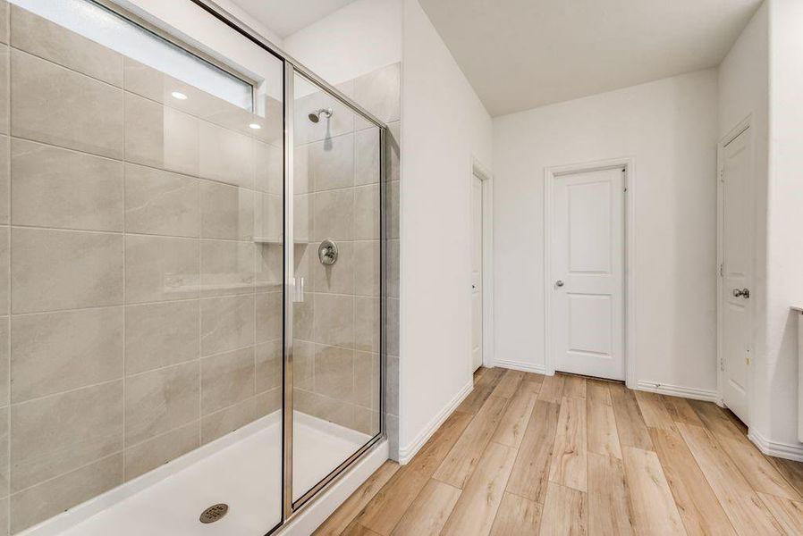 Bathroom with a shower with door and wood-type flooring