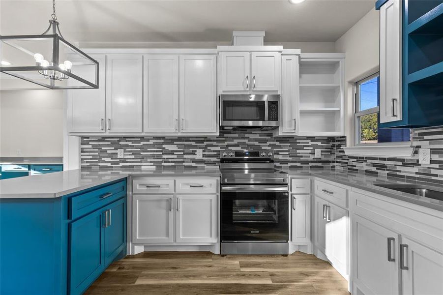 Kitchen with stainless steel appliances, white cabinetry, a peninsula, backsplash, and recessed lighting