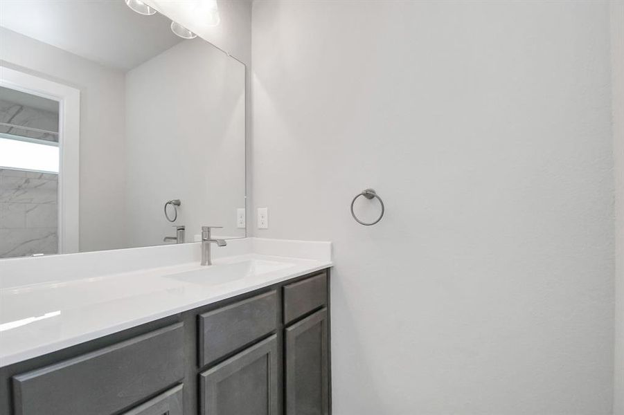 Secondary bathroom. Bath/shower combo with tile surround, dark wood cabinets complete with a beautiful light countertop, this bathroom combines style and functionality for a truly inviting ambiance.