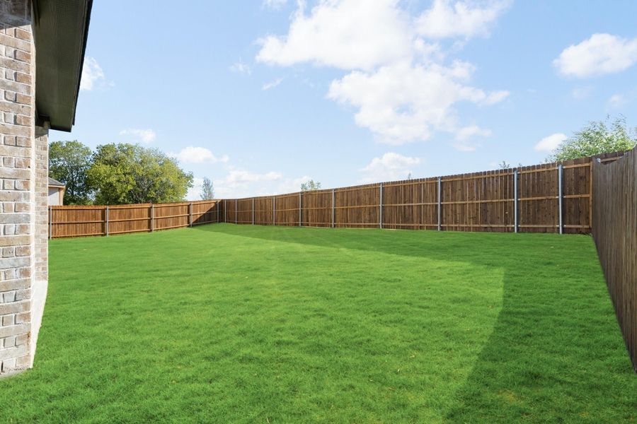 Large backyard with green grass lawn and full wood privacy fence surrounding the yard