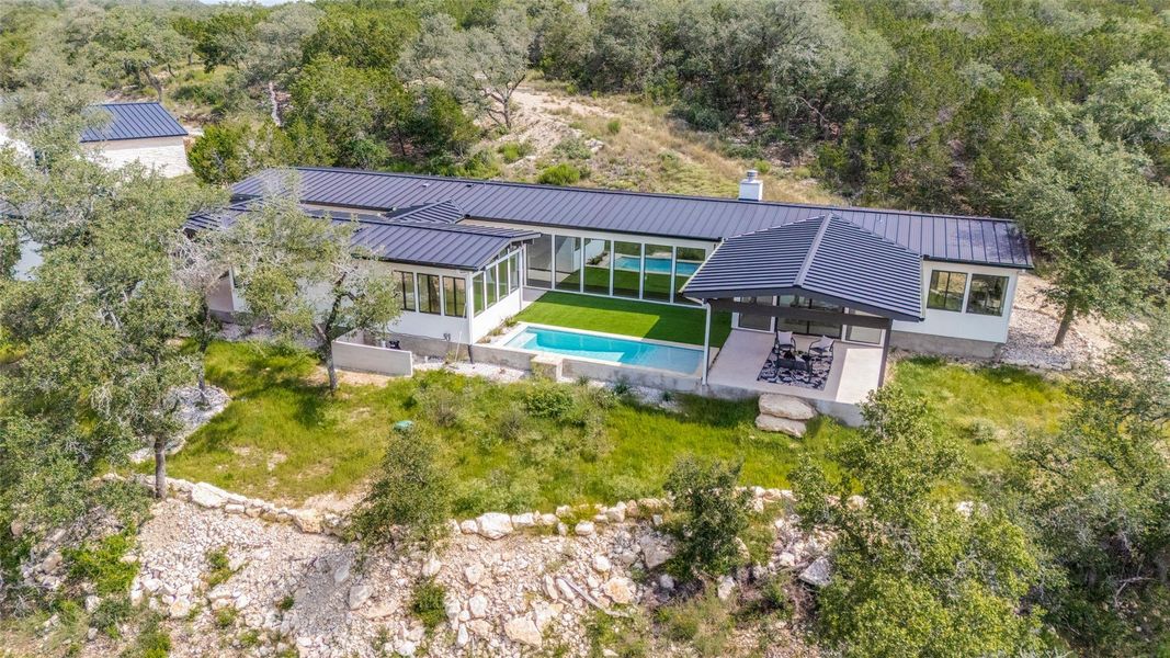 Floor-to-ceiling windows frame verdant outdoor vistas and a shimmering pool from this airy, sun-drenched living space.