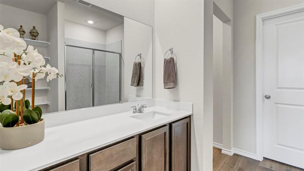 Bathroom featuring a single vanity with a white countertop, dark wood-finish cabinetry, and a large mirror Bathroom featuring a single vanity with a white countertop, dark wood-finish cabinetry, and a large mirror