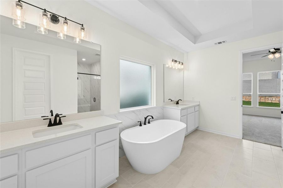 Bathroom featuring healthy amount of natural light, a marble finish shower, two vanities, and a freestanding tub Bathroom featuring healthy amount of natural light, a marble finish shower, two vanities, and a freestanding tub
