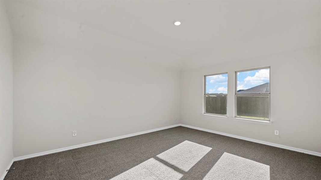 Empty room with lofted ceiling, dark colored carpet, and recessed lighting