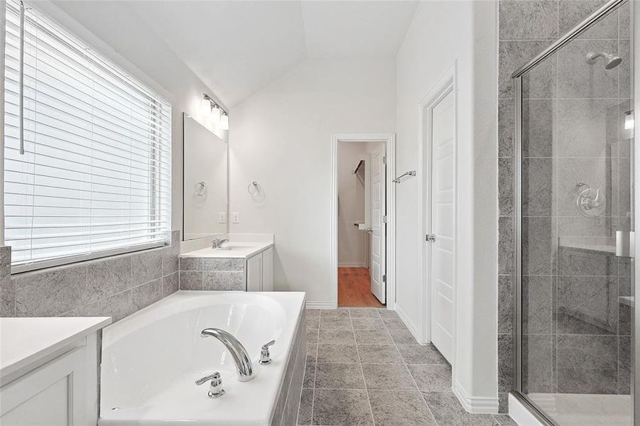 Bathroom featuring tile flooring, a healthy amount of sunlight, lofted ceiling, and independent shower and bath