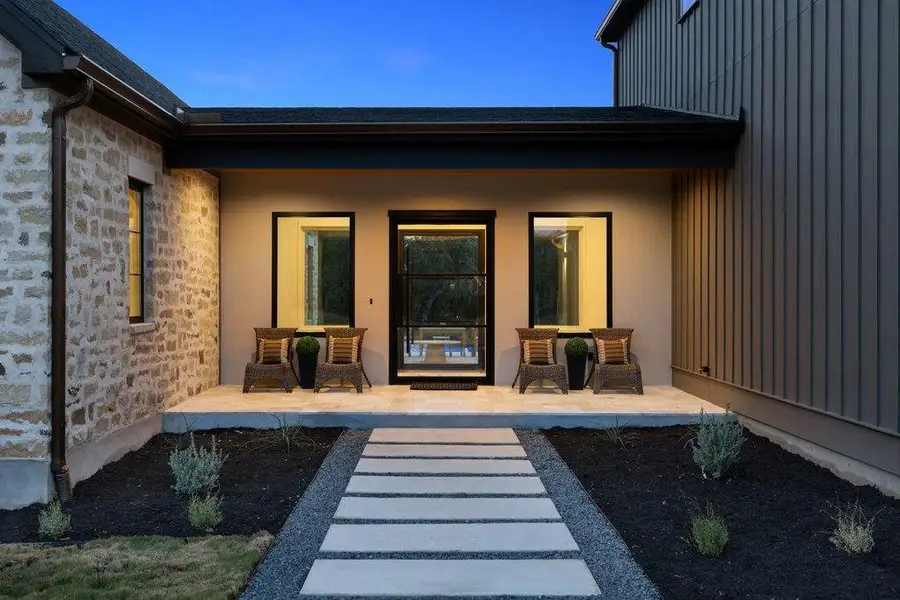A welcoming entry featuring stone and vertical siding, complemented by a modern walkway leading to the inviting front door.
