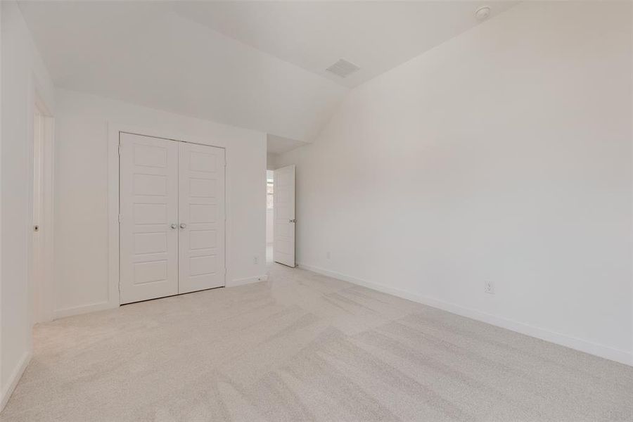 Unfurnished bedroom with light carpet, lofted ceiling, and a closet Unfurnished bedroom with light carpet, lofted ceiling, and a closet