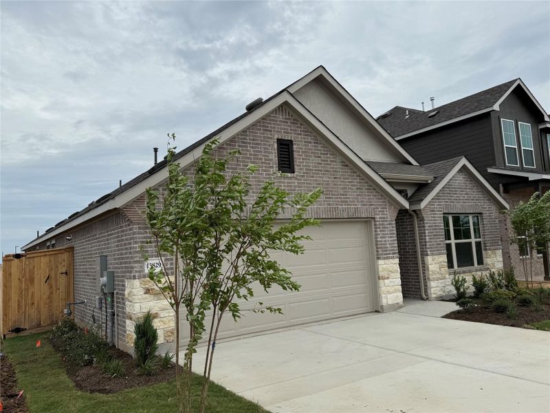 View of front of home with brick siding, roof with shingles, driveway, and stone siding View of front of home with brick siding, roof with shingles, driveway, and stone siding