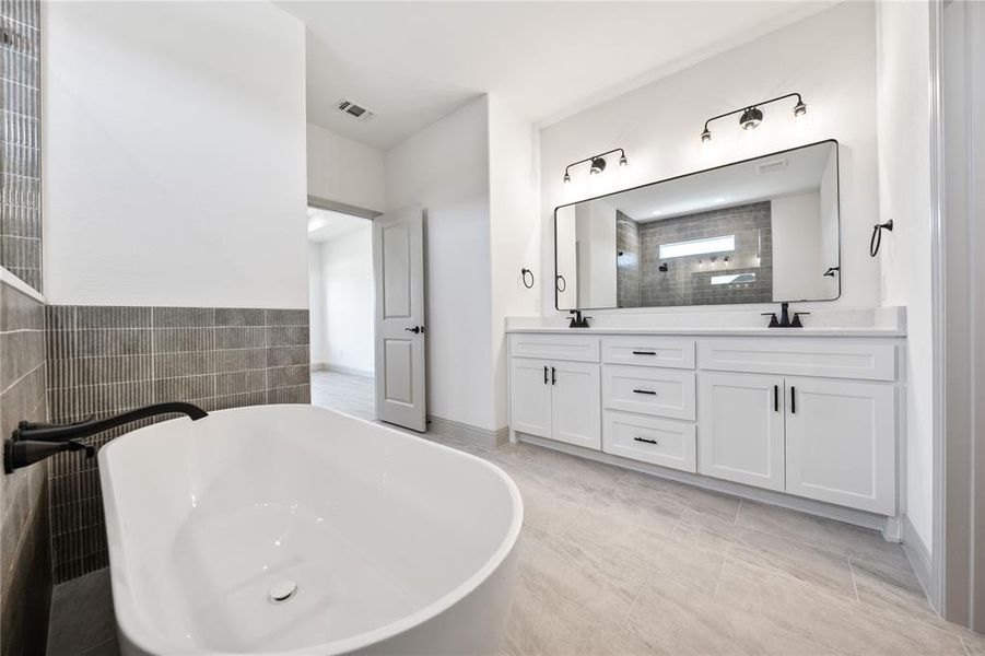 Bathroom featuring a freestanding bath, double vanity, tile walls, and tiled shower