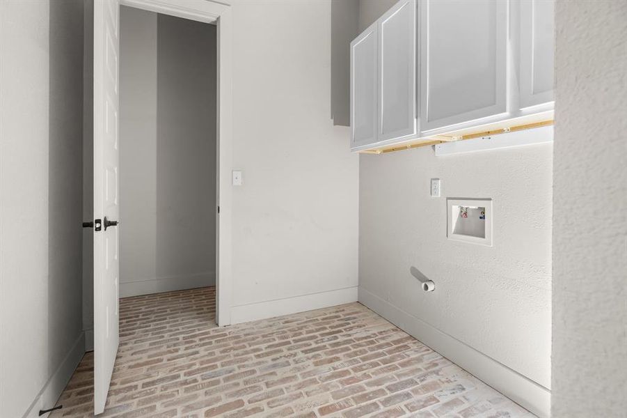 Laundry room with brick flooring, cabinet space, and hookup for a washing machine