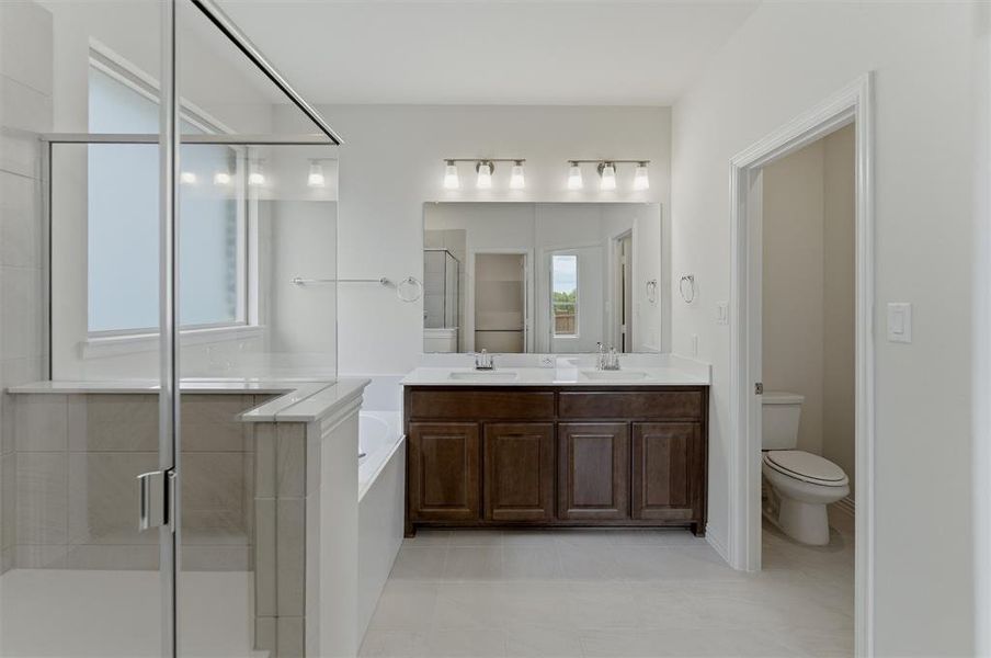 Bathroom featuring a dual vanity with dark wood cabinetry and a white countertop, two undermount sinks, and an expansive mirror