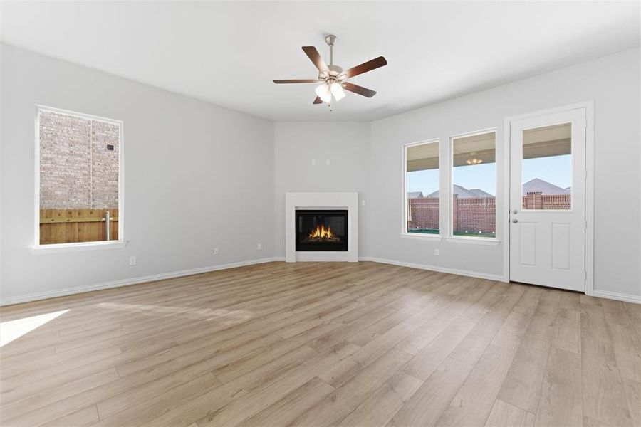 Unfurnished living room with a glass covered fireplace, light wood-style floors, and a ceiling fan