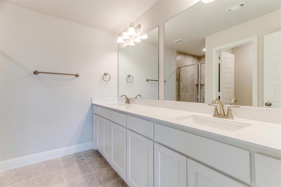Bathroom with double vanity, a stall shower, and light tile patterned floors