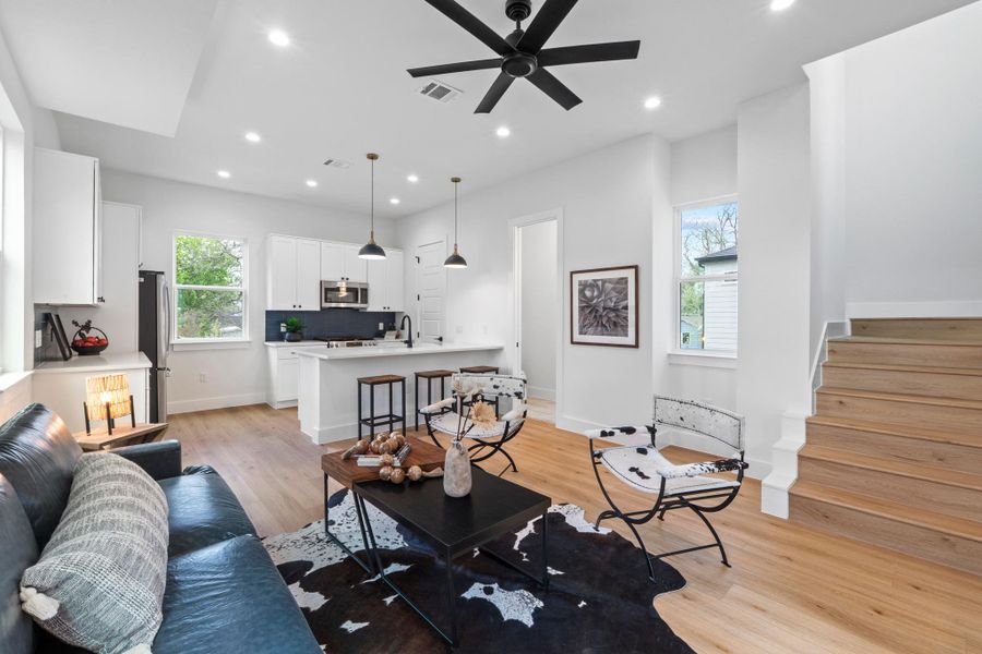 Recessed lighting and warm wood flooring enhance this open-concept layout connecting kitchen and living spaces.