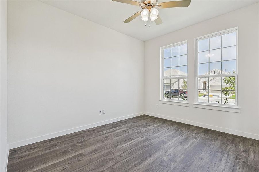 Empty room featuring ceiling fan and dark wood-type flooring