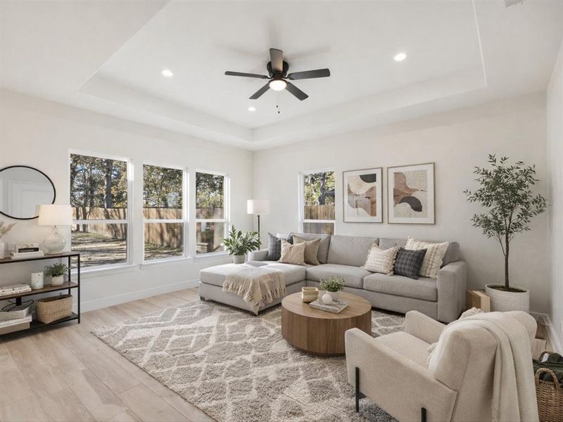 Living room featuring light wood-style flooring, a tray ceiling, ceiling fan, and recessed lighting Virtually Staged