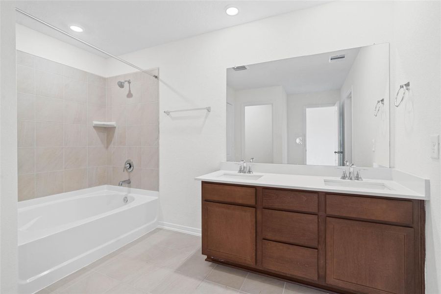 The primary bathroom offers a spacious tub/shower combination with a tiled surround, stained cabinetry topped with light countertops, dual sinks, high ceilings, neutral paint, a large mirror, and sleek, modern finishes for a polished look. The primary bathroom offers a spacious tub/shower combination with a tiled surround, stained cabinetry topped with light countertops, dual sinks, high ceilings, neutral paint, a large mirror, and sleek, modern finishes for a polished look.