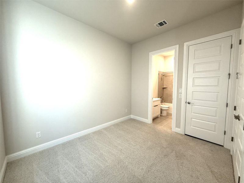 Unfurnished bedroom featuring light carpet and ensuite bathroom
