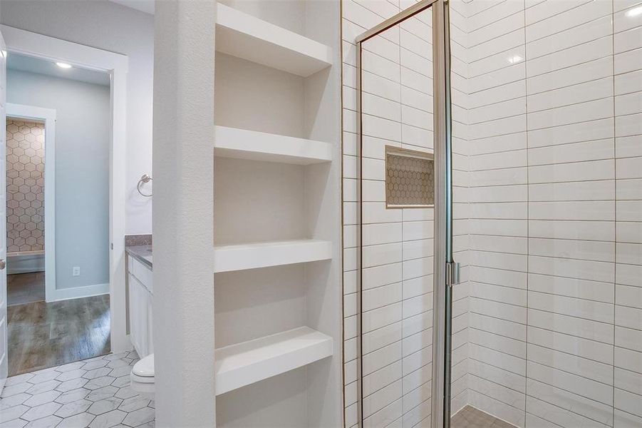 Bathroom featuring hardwood / wood-style floors, built in shelves, a shower with shower door, toilet, and vanity