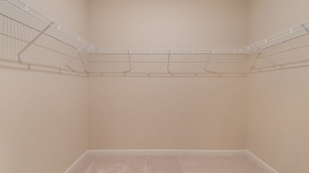 Large walk-in closet featuring generous shelving, rods, and storage space for clothing and shoes.