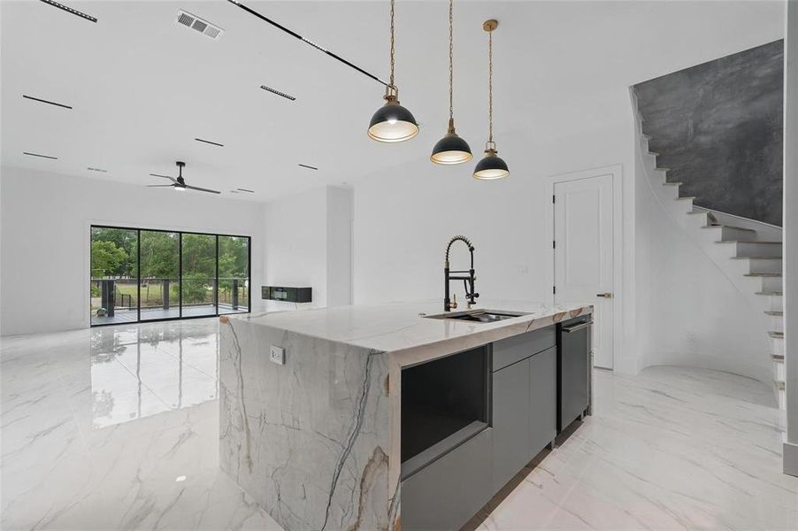 Kitchen with light marble finish flooring, pendant lighting, modern cabinets, and light stone counters Kitchen with light marble finish flooring, pendant lighting, modern cabinets, and light stone counters