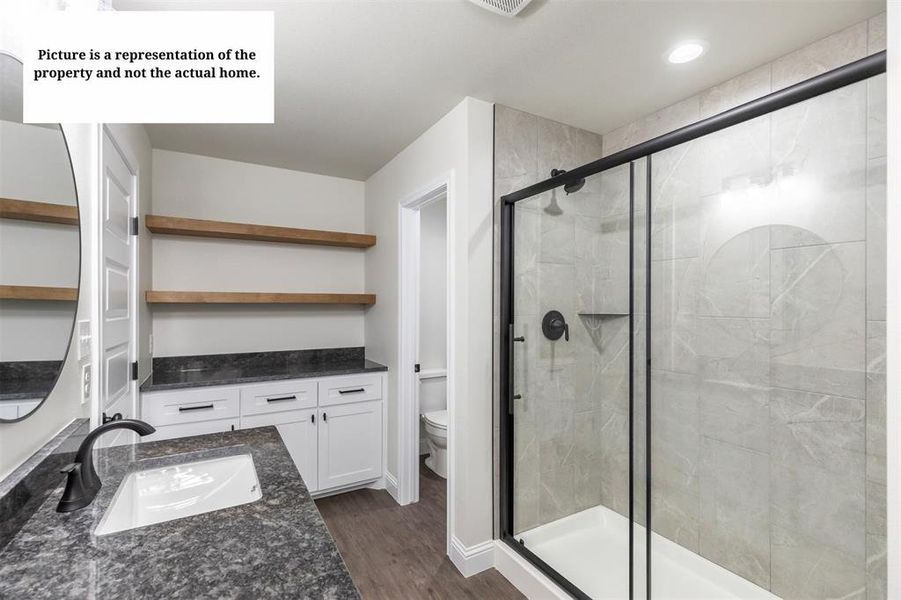 Modern bathroom featuring a walk-in shower with a black-framed glass enclosure and grey tile surround