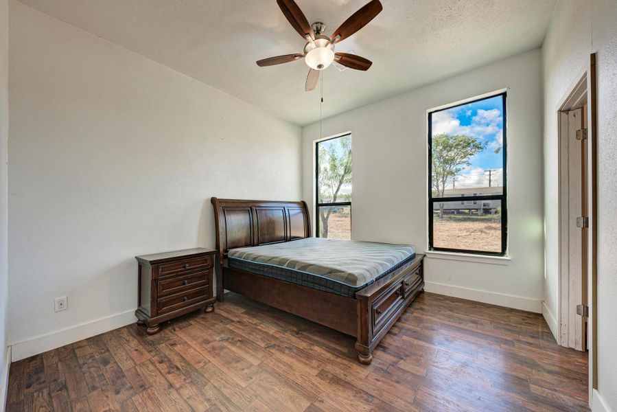 Gleaming wood floors and towering windows highlight this well-proportioned bedroom with high ceilings.