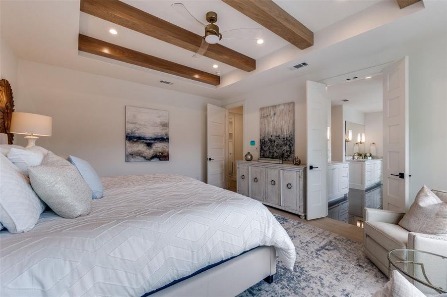 Bedroom with ensuite bathroom, beamed ceiling, visible vents, and light wood-style floors Bedroom with ensuite bathroom, beamed ceiling, visible vents, and light wood-style floors