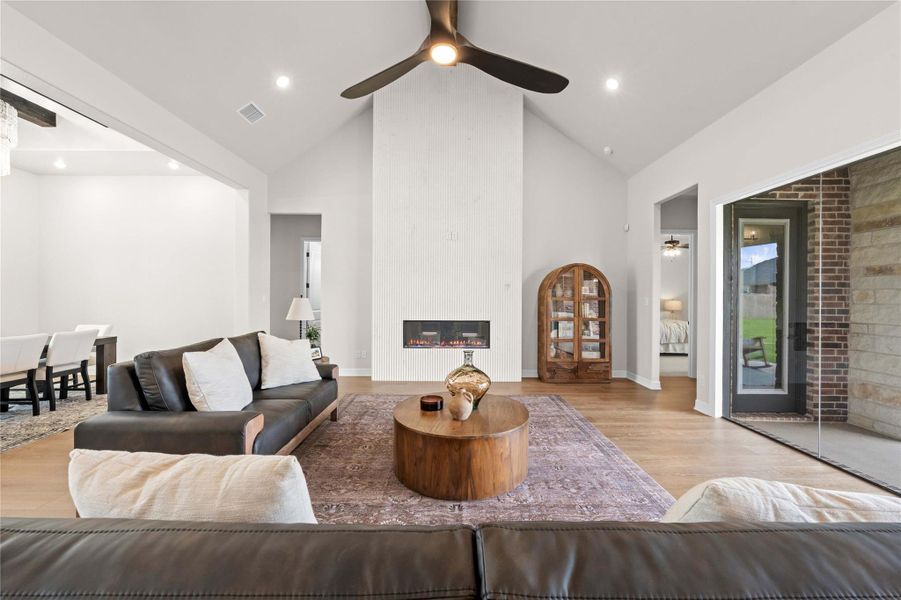 A striking fireplace with a vertical slat design anchors this naturally illuminated great room, complemented by a lofty vaulted ceiling. A striking fireplace with a vertical slat design anchors this naturally illuminated great room, complemented by a lofty vaulted ceiling.