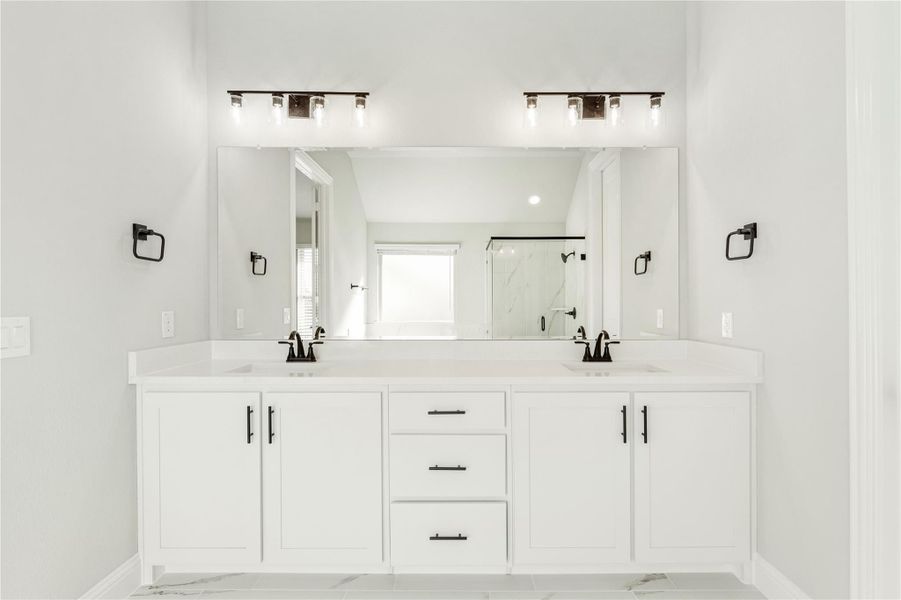 Bathroom with double vanity, white cabinets, dual sinks, large mirror, and black hardware fixtures Bathroom with double vanity, white cabinets, dual sinks, large mirror, and black hardware fixtures