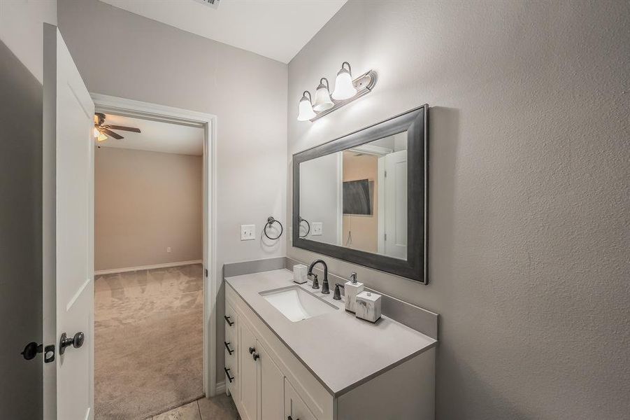 Bathroom featuring vanity, light carpet, and ceiling fan Bathroom featuring vanity, light carpet, and ceiling fan