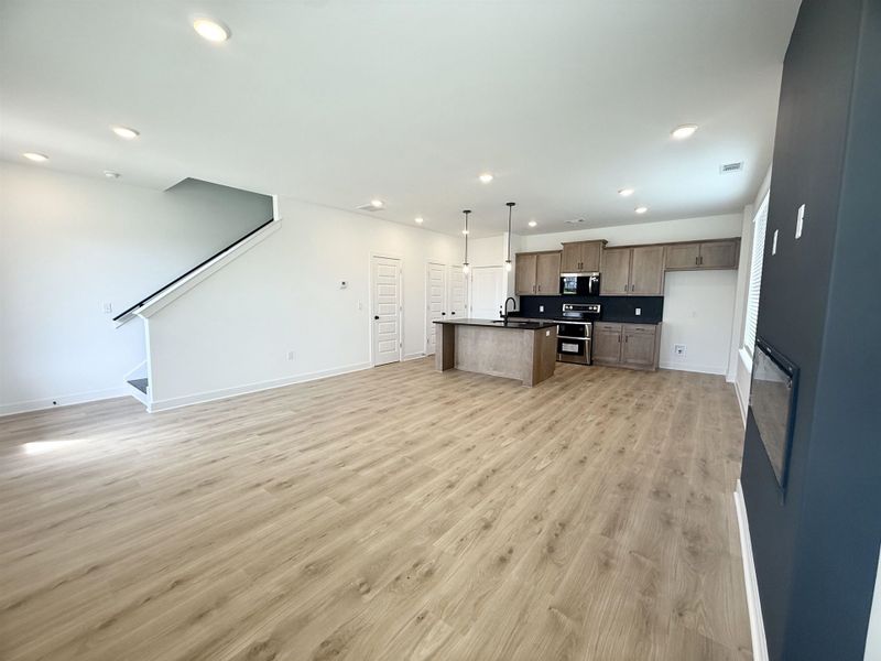 Kitchen with open floor plan, stainless steel appliances, recessed lighting, dark countertops, and light wood finished floors