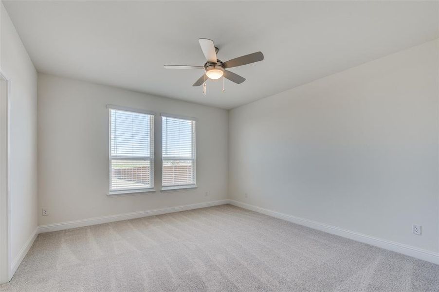 Unfurnished room with light colored carpet and a ceiling fan