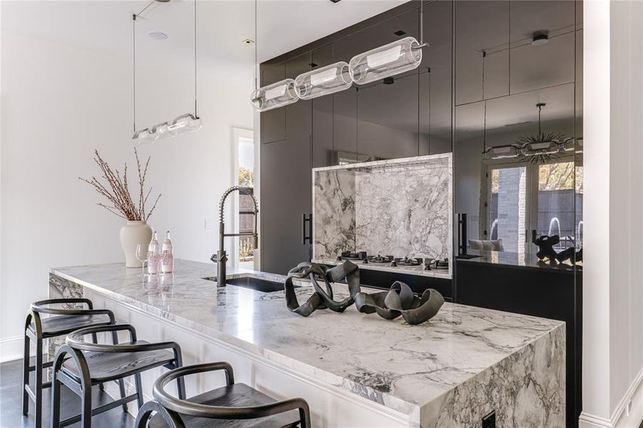 Kitchen featuring a sink, dark cabinets, and light stone counters
