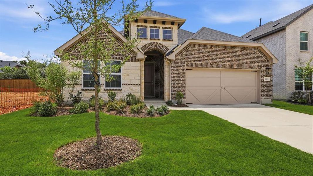 Brick and stone facade featuring a prominent arched entryway, a double-car garage with carriage-style doors, and decorative landscaping Brick and stone facade featuring a prominent arched entryway, a double-car garage with carriage-style doors, and decorative landscaping