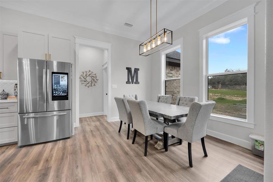 Dining space with light hardwood / wood-style floors and crown molding