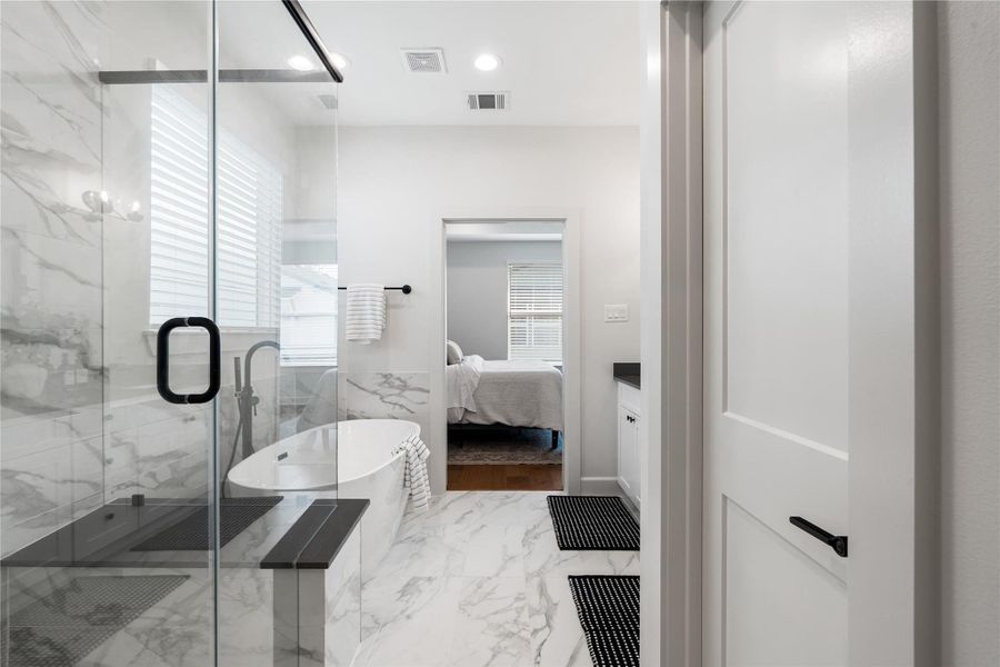 Overview of the spacious primary bathroom with a walkway to the primary bedroom