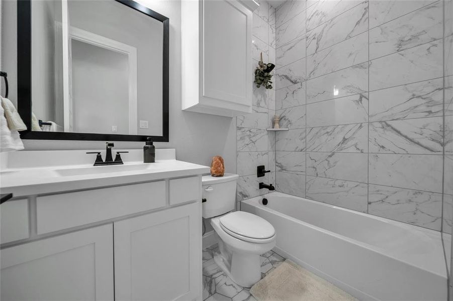 Bathroom featuring tub / shower combination, vanity, and light marble finish floors Bathroom featuring tub / shower combination, vanity, and light marble finish floors