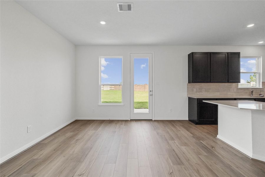 Create lasting memories with family and friends in this inviting dining room! It showcases high ceilings, recessed lighting, custom paint, stunning vinyl plank flooring, and access door to the rear patio and backyard.
